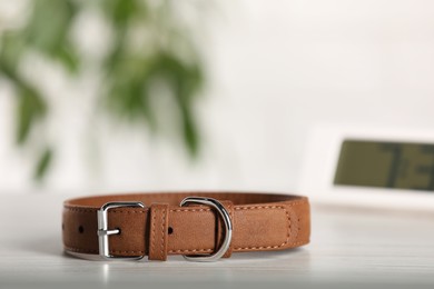 Photo of Brown leather dog collar on table against blurred background, space for text