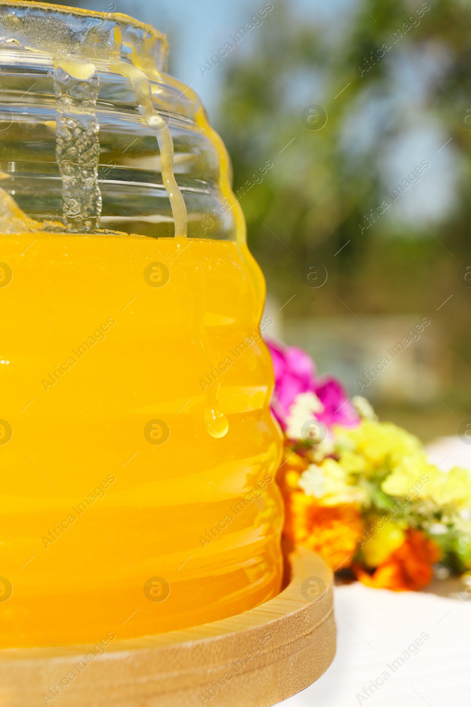 Photo of Delicious fresh honey in glass jar on white wooden table, closeup