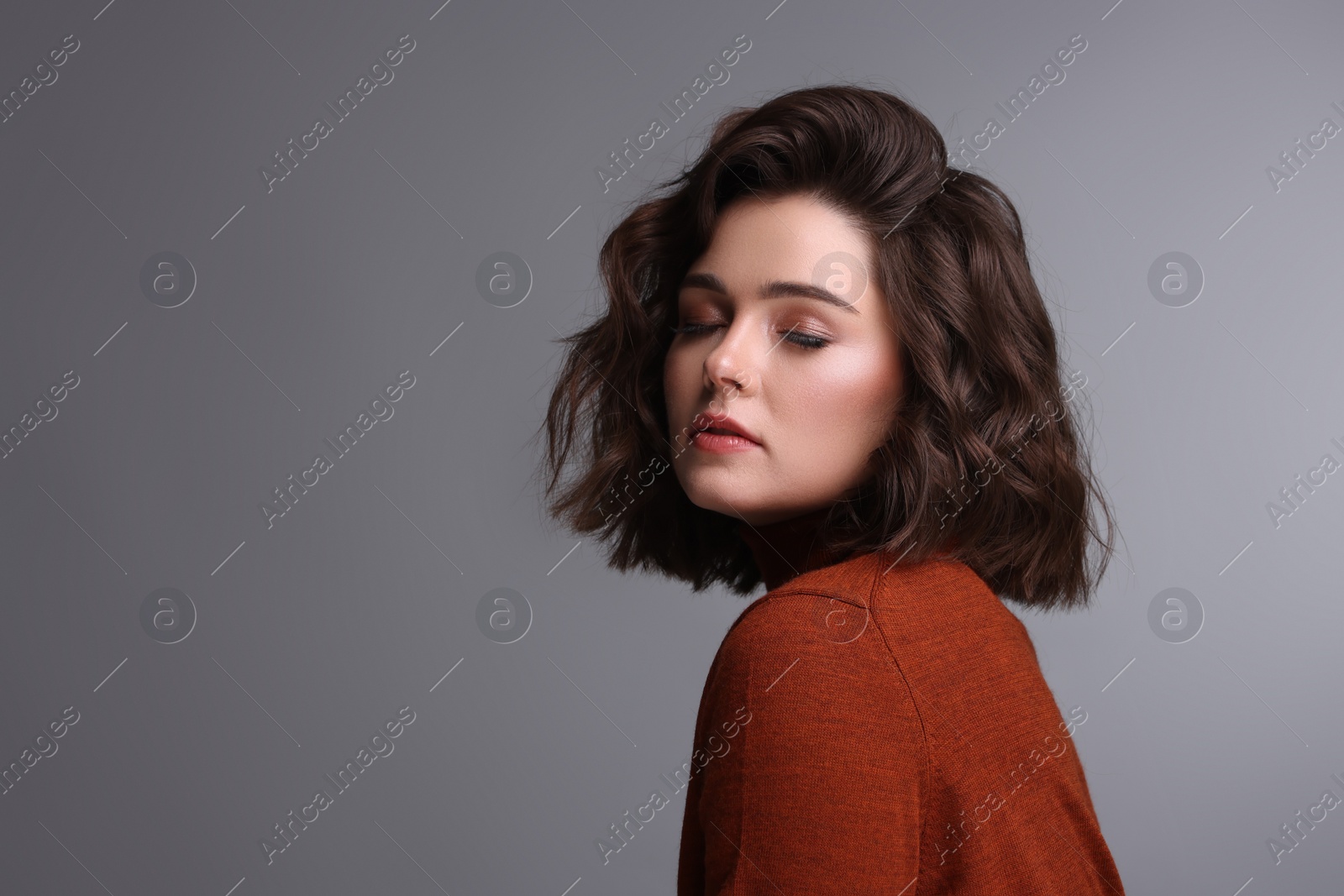 Photo of Portrait of beautiful young woman with wavy hairstyle on grey background. Space for text