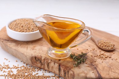 Photo of Jug of natural oil and mustard seeds on wooden table