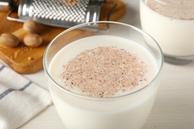 Photo of Milk with nutmeg powder on white table, closeup