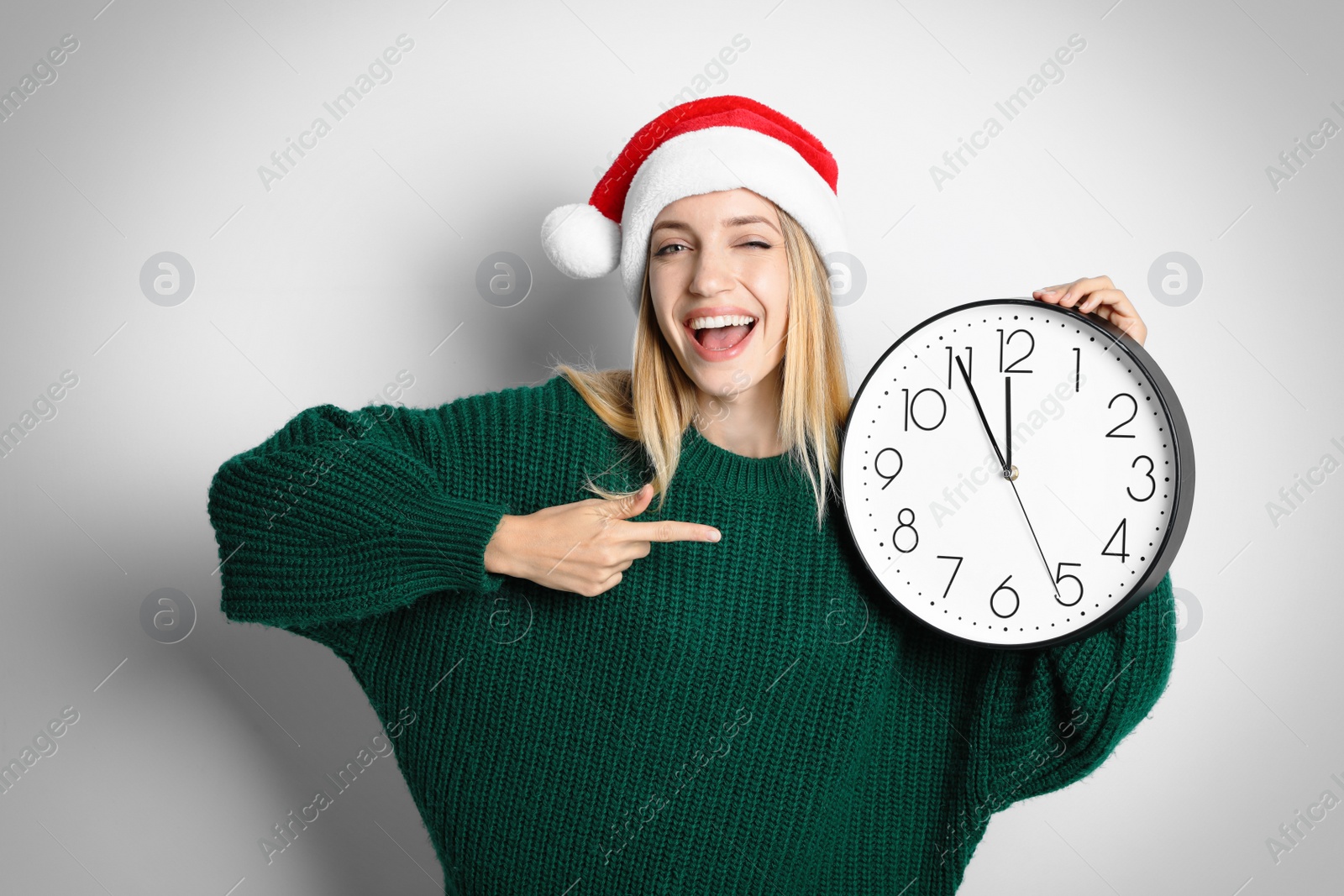 Photo of Woman in Santa hat with clock on white background. New Year countdown