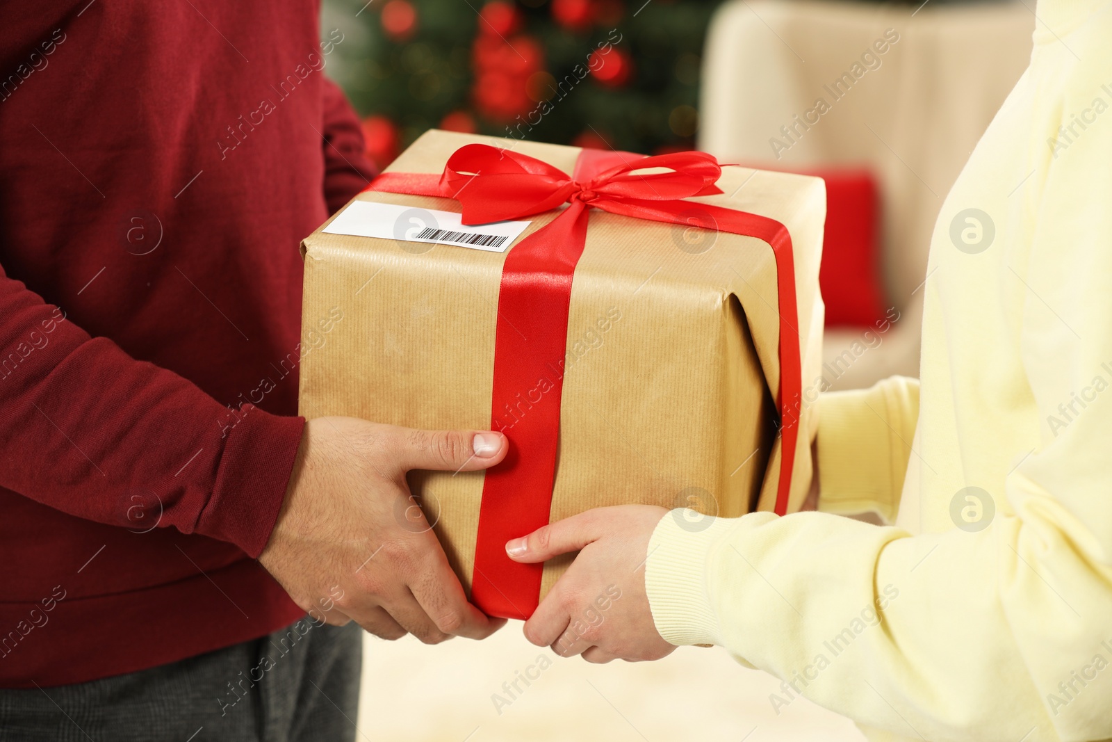 Photo of Man giving woman Christmas gift box received by mail indoors, closeup