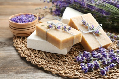 Photo of Handmade soap bars with lavender flowers on brown wooden table