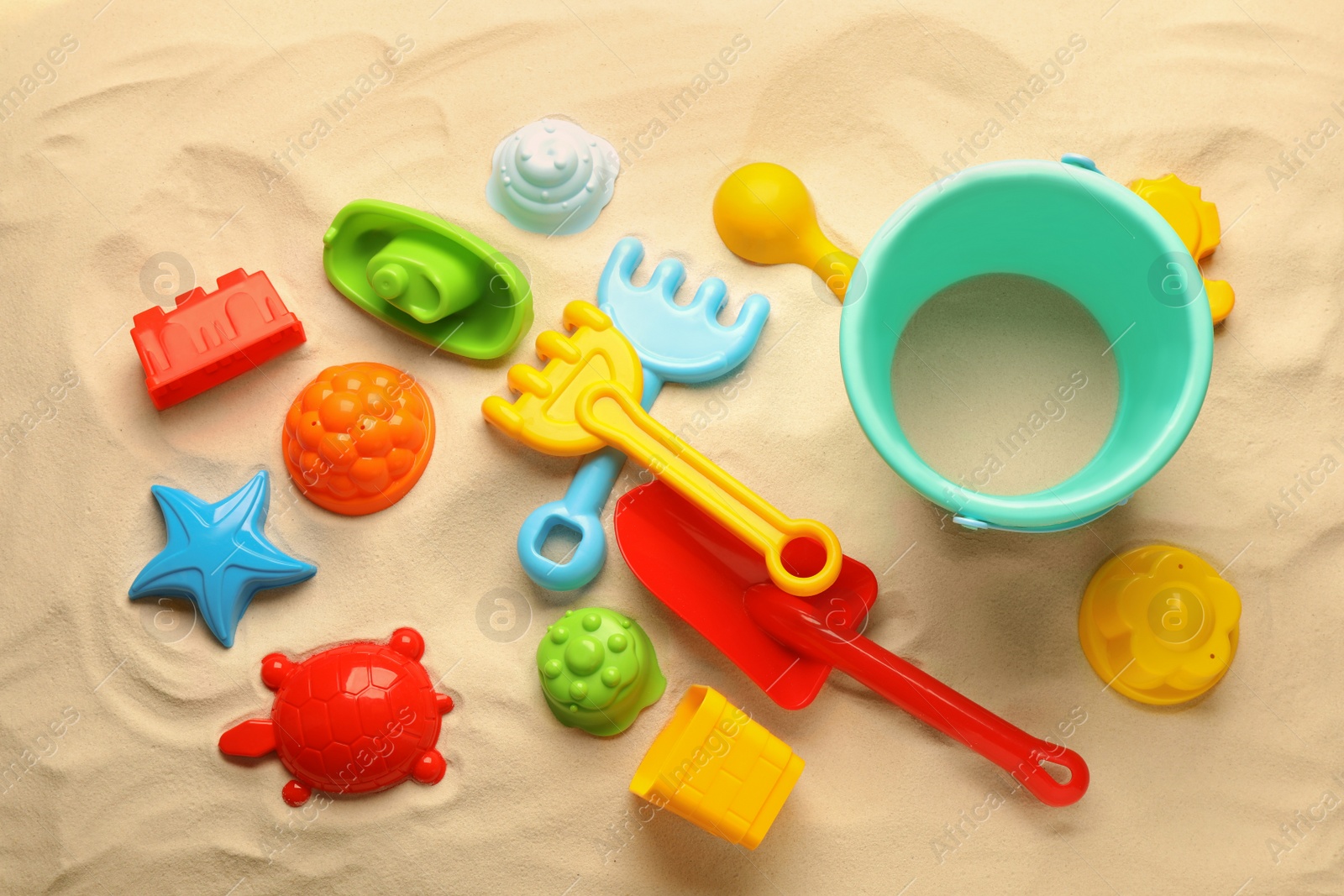 Photo of Beach toy kit on sand, flat lay. Outdoor play