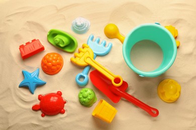 Photo of Beach toy kit on sand, flat lay. Outdoor play