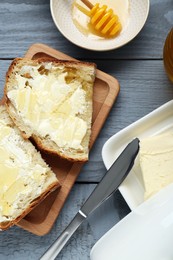 Photo of Slices of bread with butter and honey on grey wooden table, flat lay