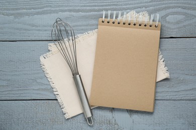 Blank recipe book and whisk on grey wooden table, flat lay. Space for text