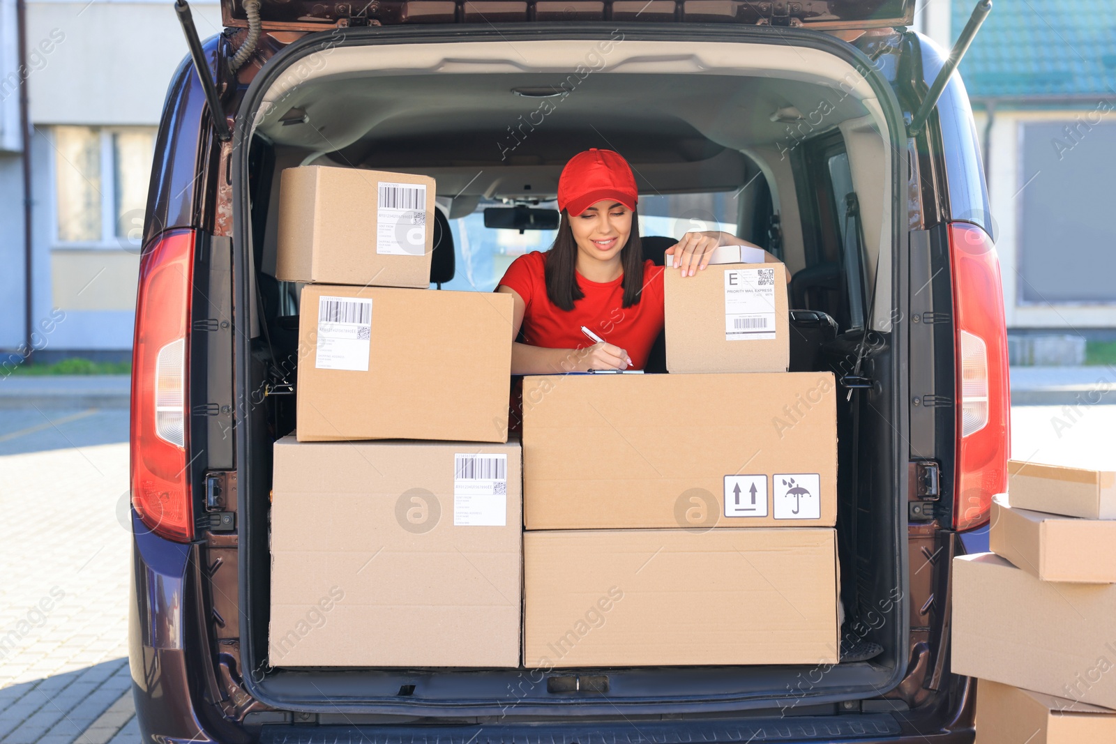 Photo of Courier with clipboard checking packages in delivery van