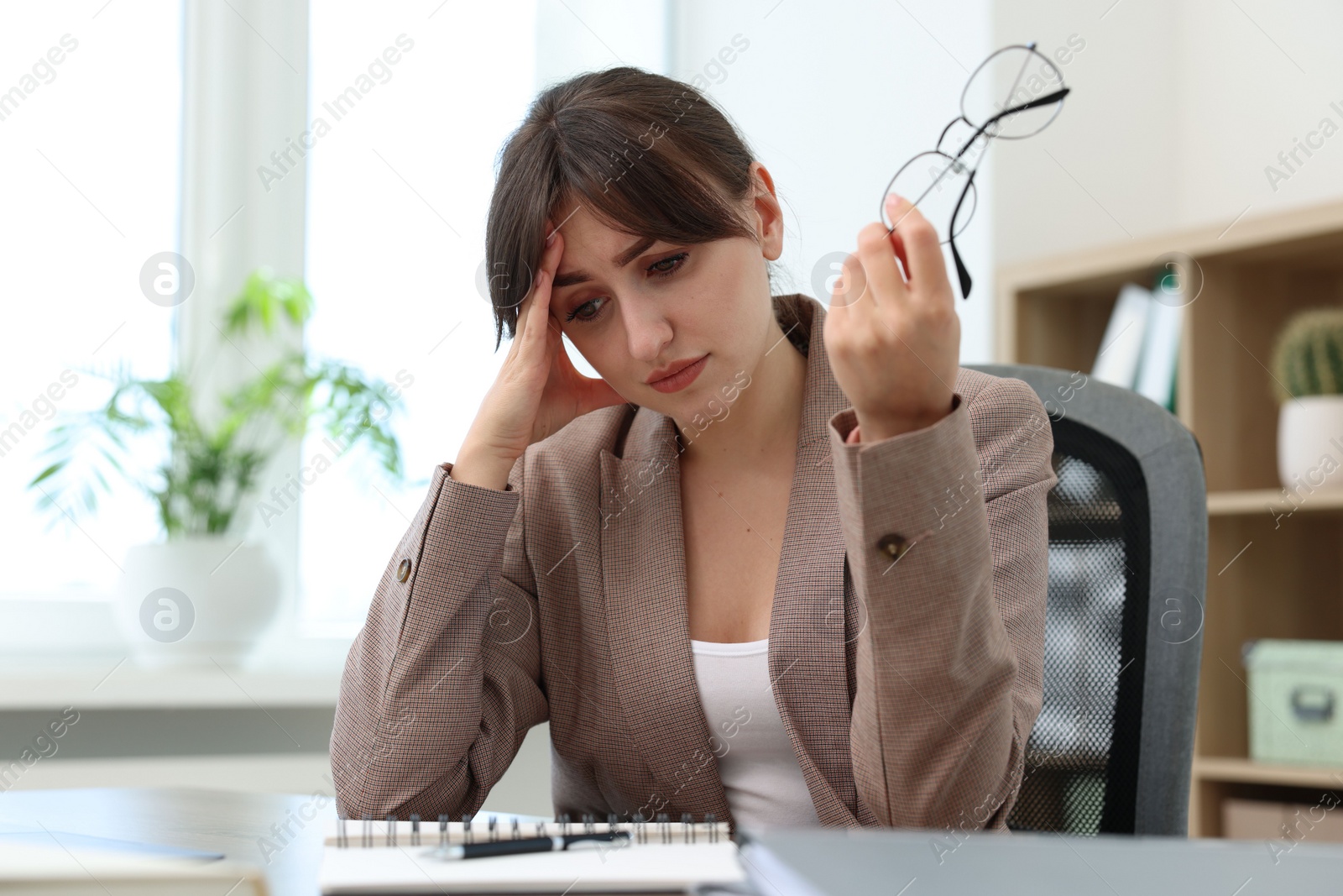 Photo of Overwhelmed woman suffering at table in office