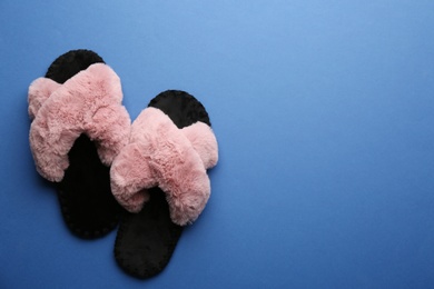Pair of soft slippers on blue background, flat lay. Space for text