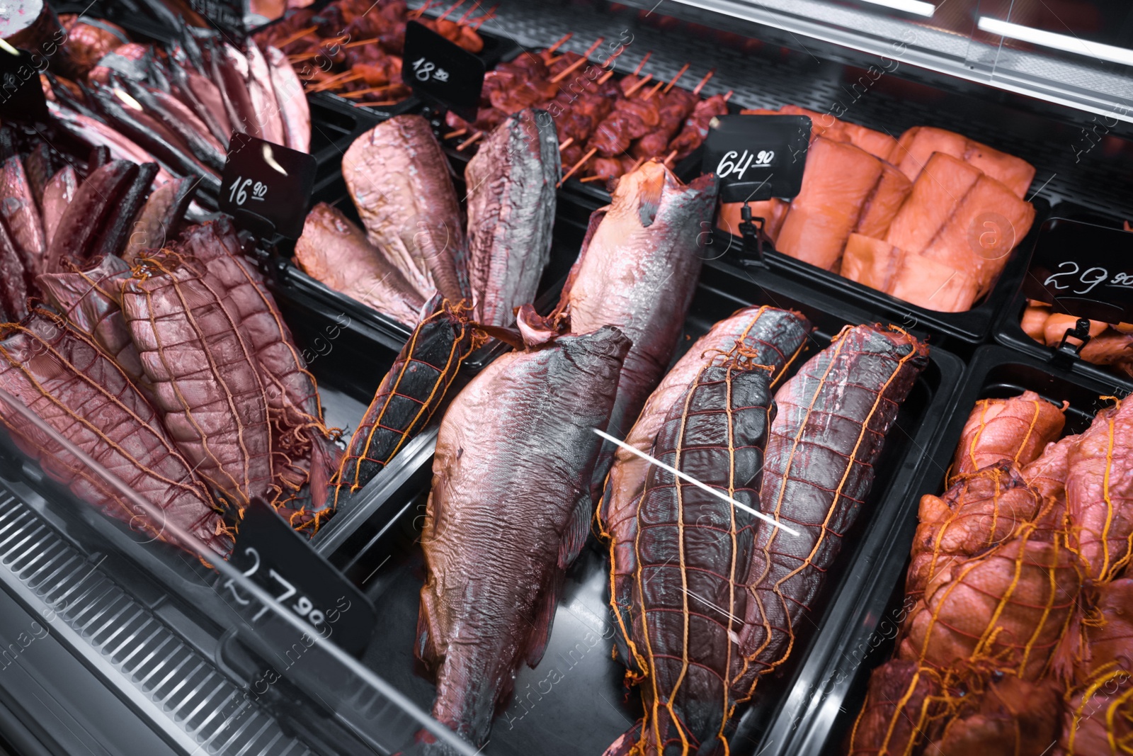 Photo of Showcase with different smoked fish in supermarket