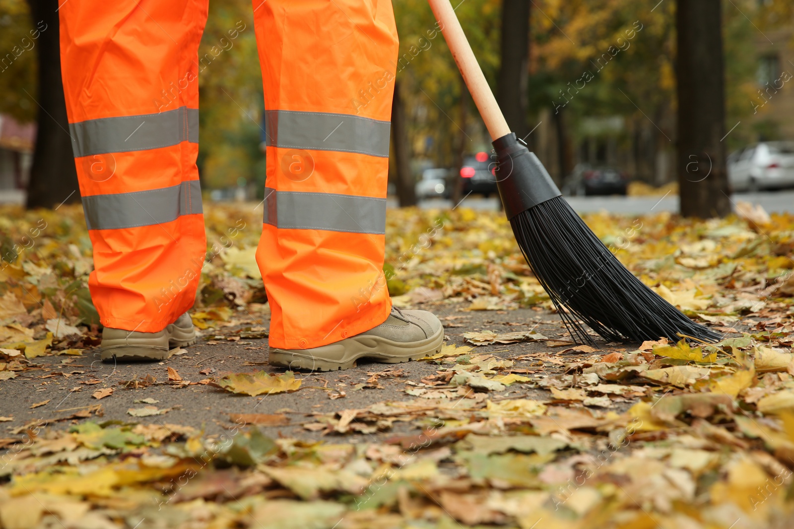 Photo of Street cleaner sweeping fallen leaves outdoors on autumn day