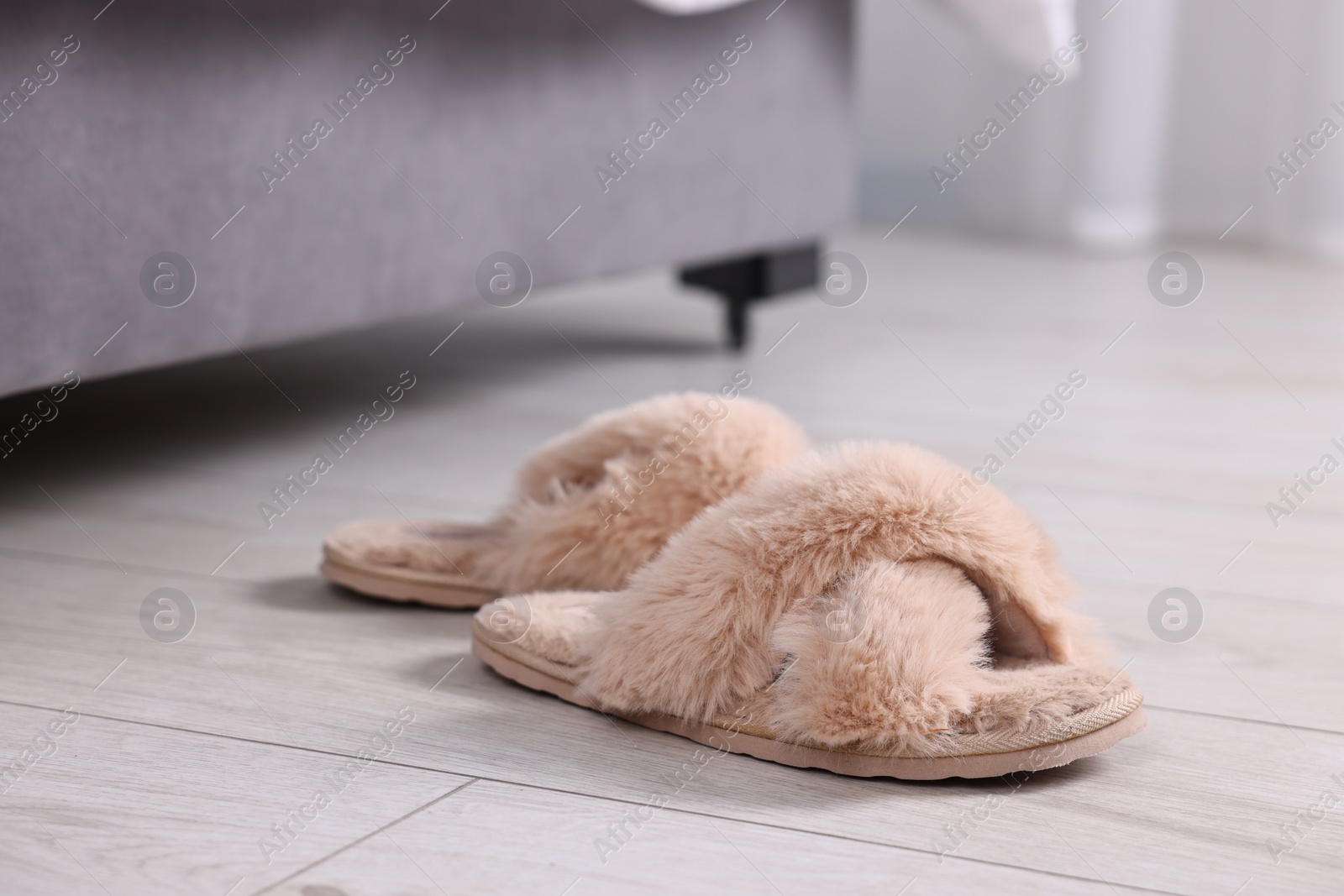 Photo of Beige soft slippers on light wooden floor at home