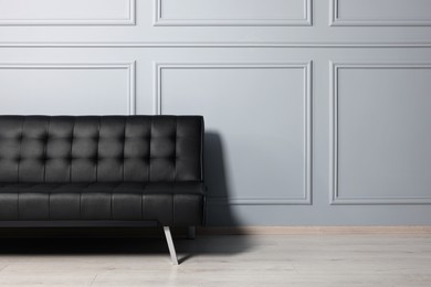 Photo of Stylish leather sofa near white wall in room. Interior design