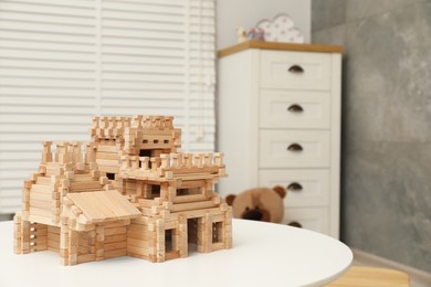 Photo of Wooden castle on white table indoors, space for text. Children's toy