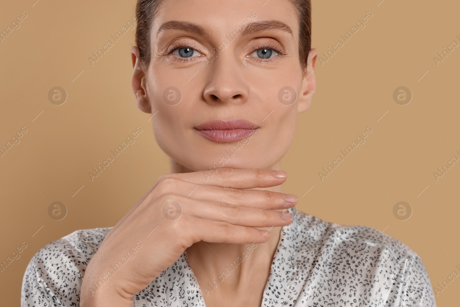 Photo of Woman massaging her face on beige background