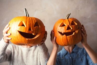 Photo of Women holding Halloween pumpkin head jack lanterns against color background