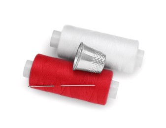 Photo of Thimble, spools of sewing threads and needle isolated on white, top view
