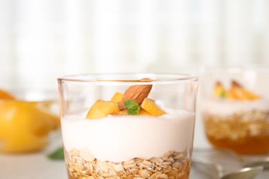 Tasty peach dessert with yogurt and granola on table, closeup