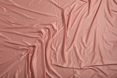 Photo of Crumpled coral fabric as background, closeup view