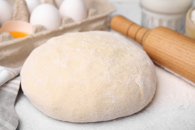 Dough, rolling pin and ingredients on white table, closeup