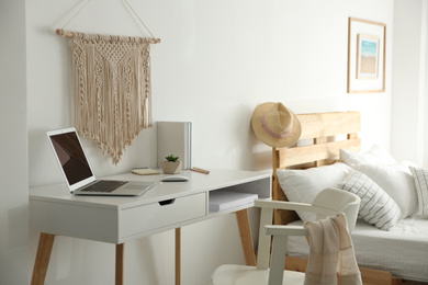 Stylish room interior with workplace and bed