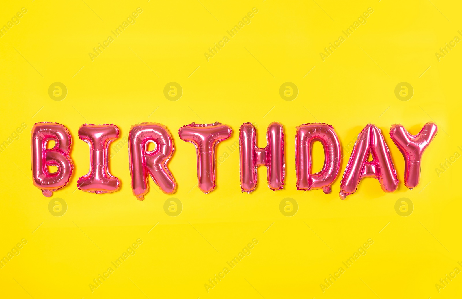 Photo of Word BIRTHDAY made of pink foil balloons letters on yellow background