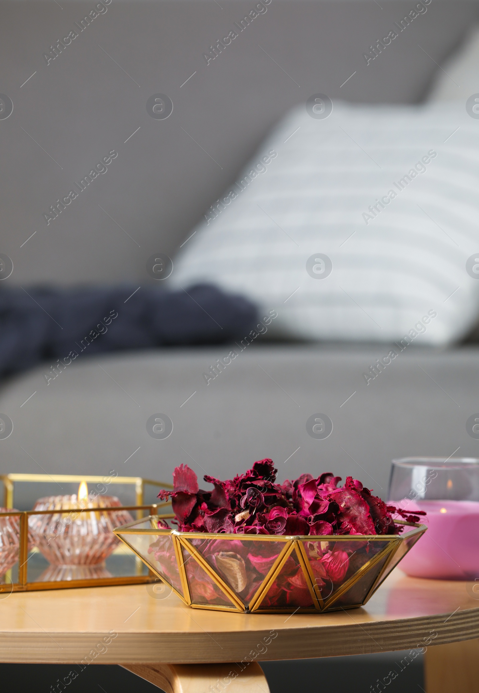 Photo of Aromatic potpourri of dried flowers in decorative bowl and burning candles on table indoors, space for text