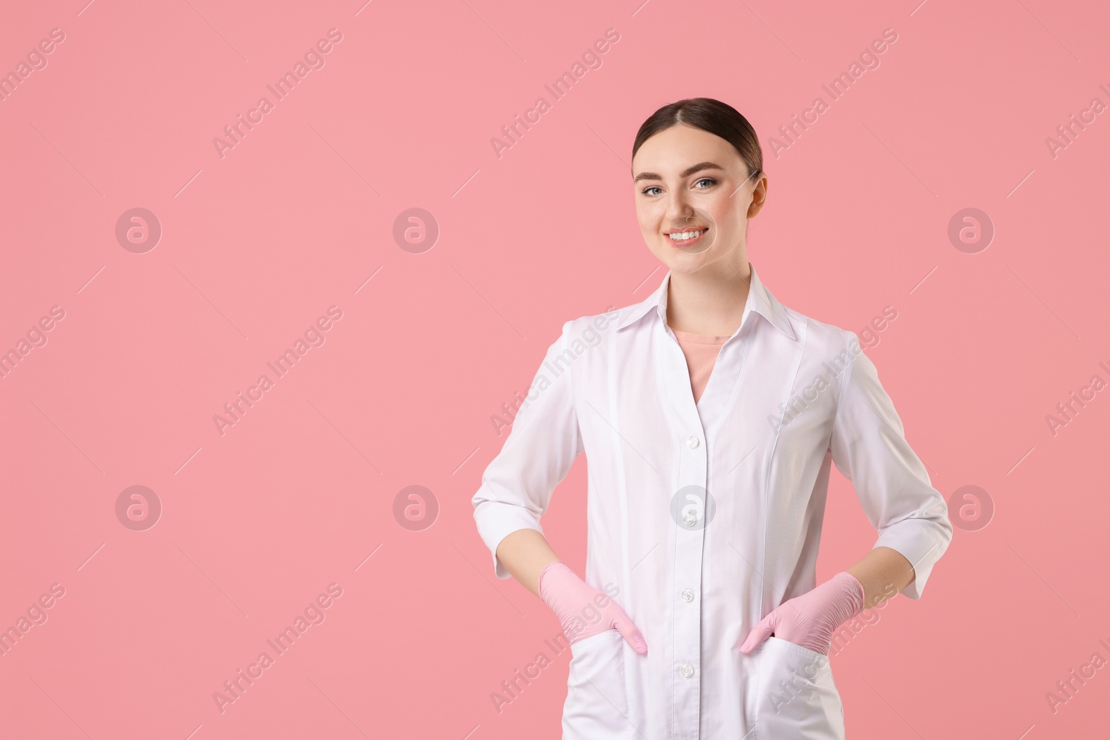 Photo of Cosmetologist in medical uniform on pink background, space for text