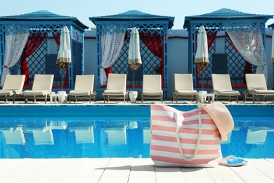 Beach accessories on wooden deck near swimming pool. Space for text