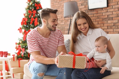 Happy couple with baby celebrating Christmas together at home