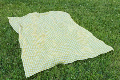 Photo of Checkered picnic tablecloth on fresh green grass outdoors