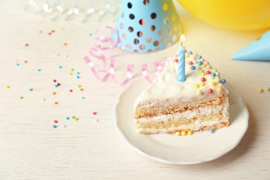 Slice of delicious birthday cake with candle on table