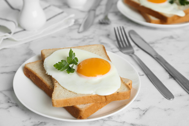 Photo of Tasty fried chicken egg with bread and parsley on white marble table, closeup