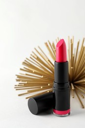 Photo of Beautiful pink lipstick and golden decoration on white background