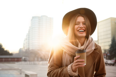 Photo of Young woman with cup of coffee on city street in morning