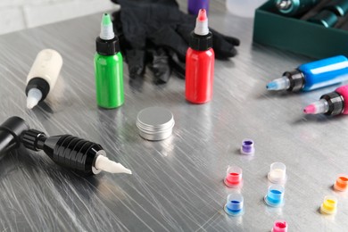 Photo of Modern professional tattoo machine, colorful inks and ointment on table in salon