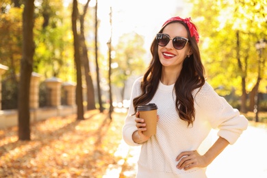 Photo of Beautiful woman with cup of coffee in park. Autumn walk
