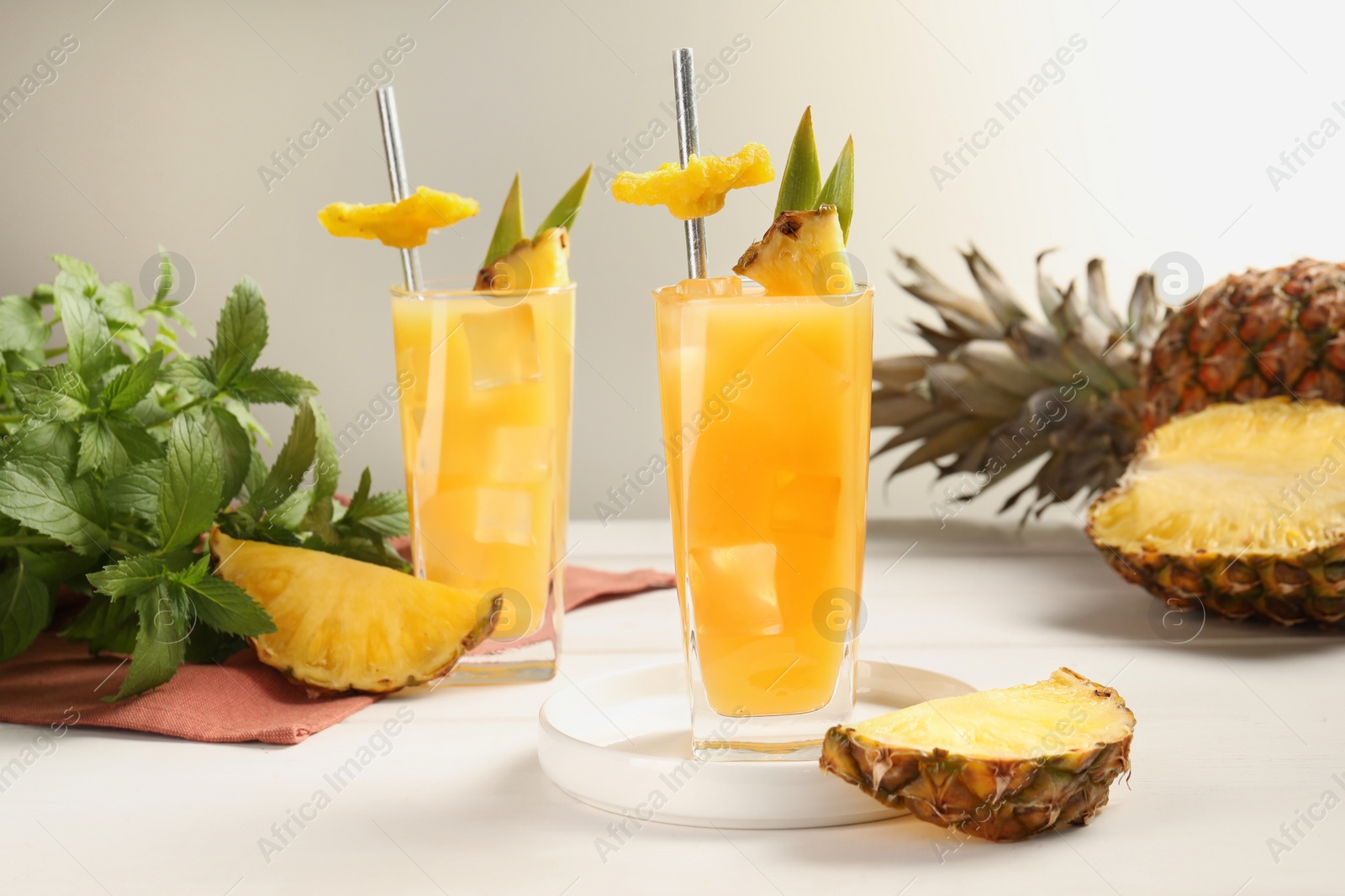 Photo of Tasty pineapple cocktail, sliced fruit and mint on white table