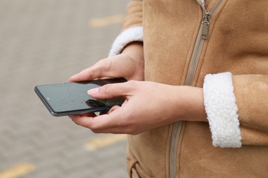 Woman holding damaged smartphone outdoors, closeup. Device repairing