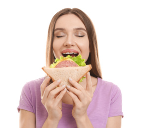 Young woman eating tasty sandwich on white background