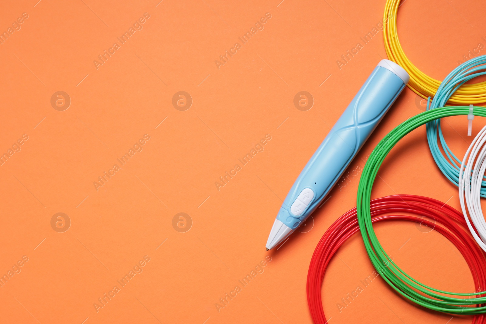 Photo of Stylish 3D pen and colorful plastic filaments on orange background, flat lay. Space for text