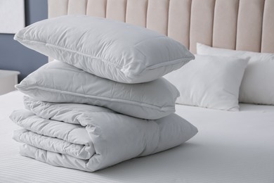 Photo of Soft folded blanket and pillows on bed indoors, closeup