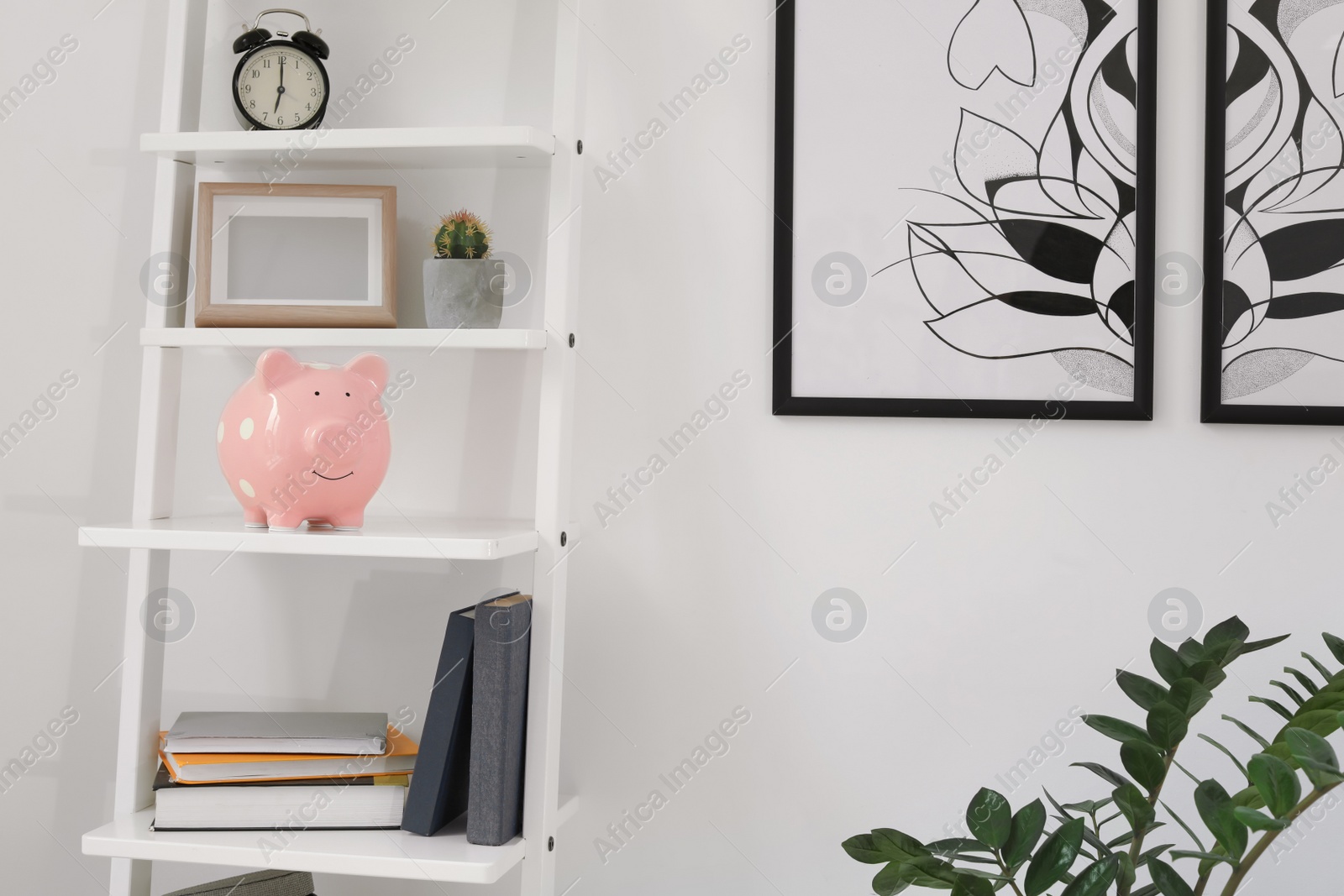 Photo of Shelving unit with decorative interior elements and piggy bank near white wall