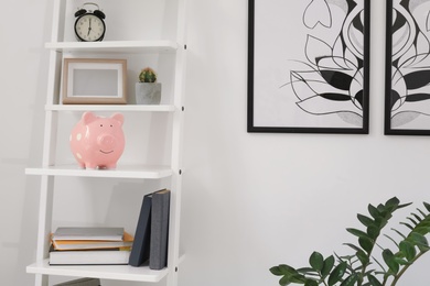 Shelving unit with decorative interior elements and piggy bank near white wall