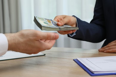 Cashier giving money to businessman at desk in bank, closeup