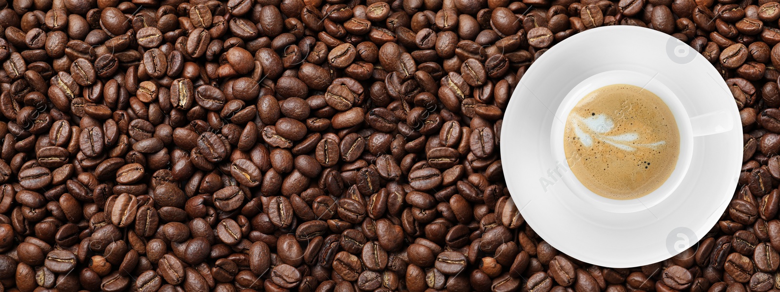 Image of Cup of tasty aromatic coffee on roasted beans, top view. Banner design