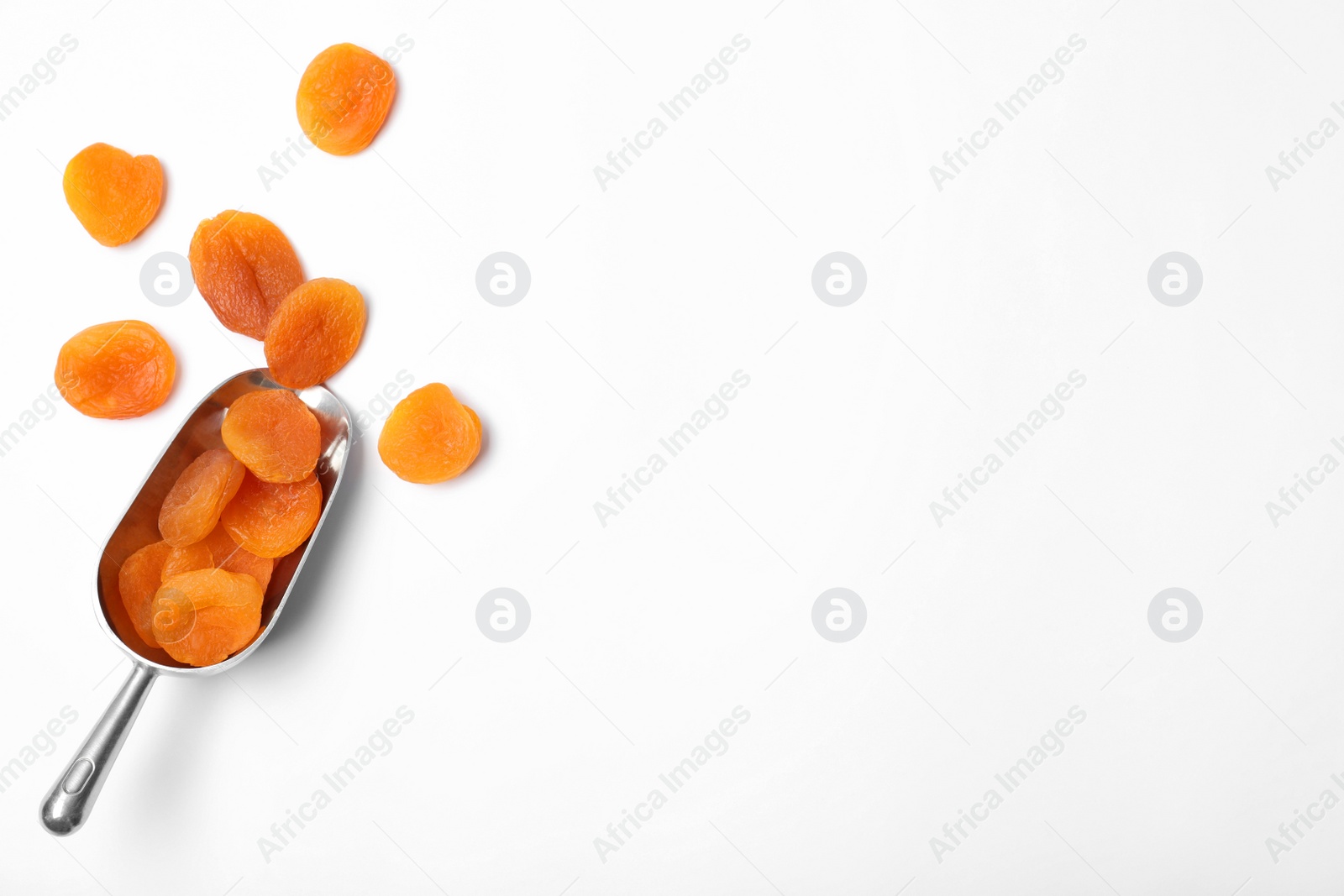 Photo of Scoop of dried apricots on white background, top view with space for text. Healthy fruit