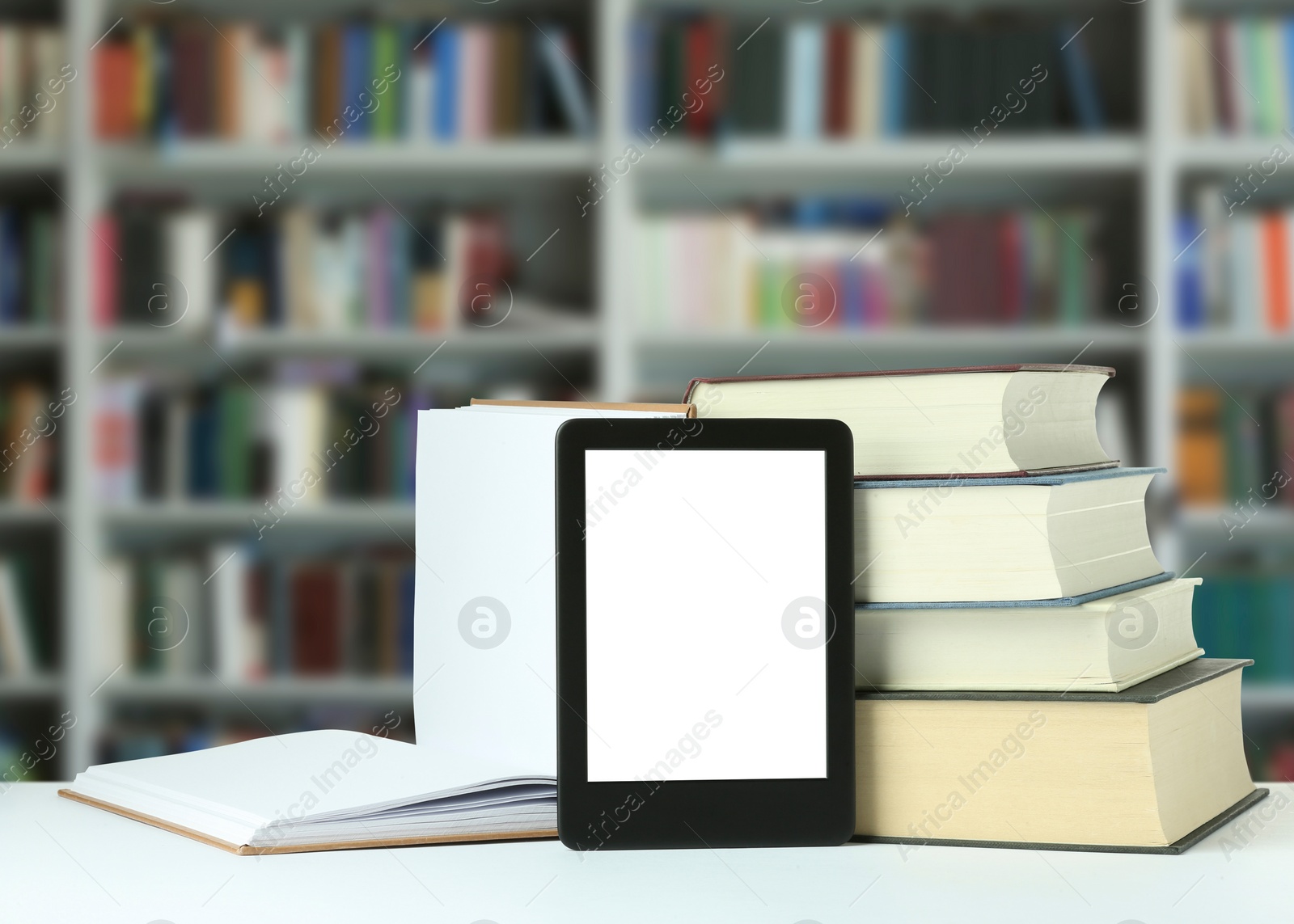 Image of Hardcover books and modern e-book on white table in library